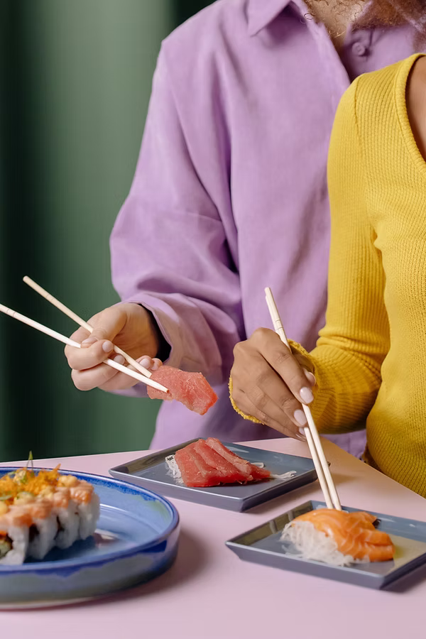 Naiset syömässä Sushia puikoilla